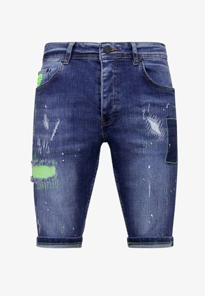 Donkerblauwe denimshorts met versleten details en groene accenten. Kenmerken zijn onder andere zakken, een knoopsluiting en rafelige hemden met verfspetters.