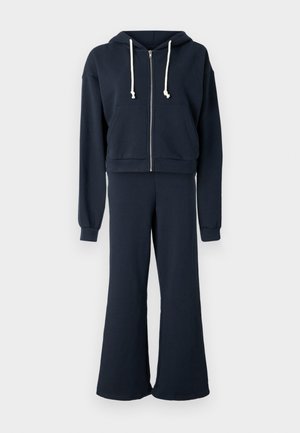 Sweatshirt com capuz azul-marinho em algodão, com fecho de correr, cordões e bolso frontal, combinado com calças com bainha rodada a condizer. Textura suave e corte descontraído.