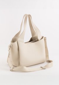Beige Leder-Tote-Bag mit texturiertem Oberflächenfinish, doppelten Griffen und verstellbarem Schultergurt. Minimalistisches Design ohne sichtbare Hardware.