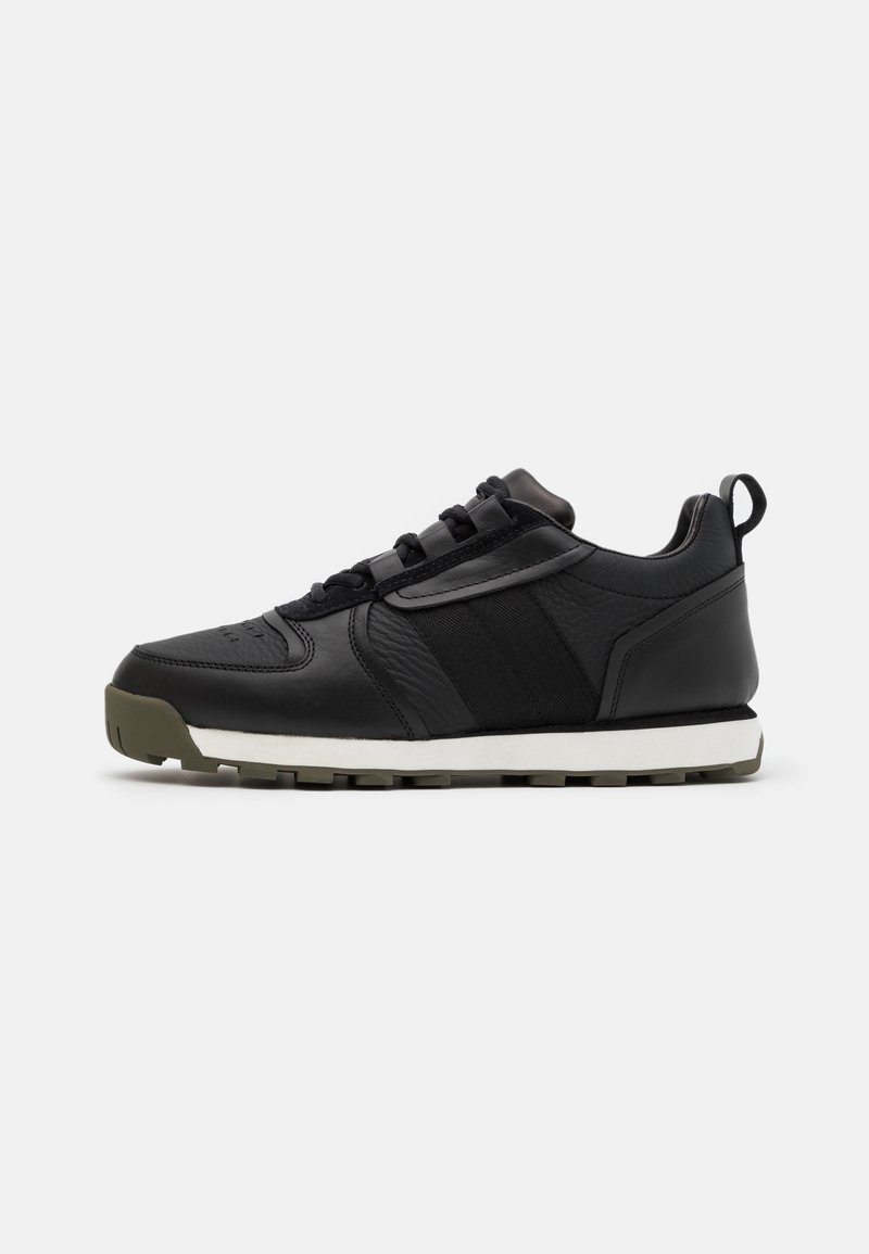 Black athletic shoes with a leather upper, suede accents, textile detailing, white midsole, and textured rubber outsole.