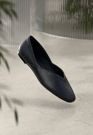 Svarta läderballettskor med spetsig tå och ett V-format utskärning på ovandelen. Slät textur och minimalistisk design med en smal klack.
