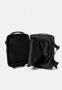 Sac à dos rigide gris avec un intérieur noir, une poche en filet et des bretelles ajustables. Compartiments zippés pour un rangement organisé. Texture lisse.
