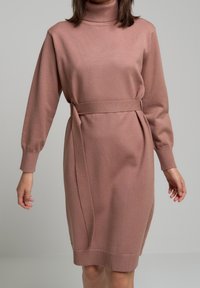 Robe en maille rose poudré avec un col montant, des manches longues et une ceinture à nouer à la taille, dotée de poignets et d’un ourlet côtelés.