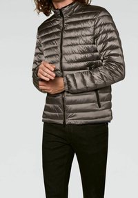 Padded gray jacket with a high collar, zip front, and side pockets. Features quilted design and smooth texture.