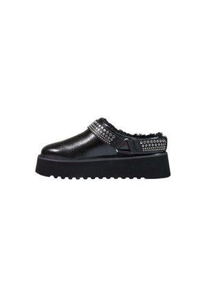 Czarny but na platformie typu slip-on z ozdobnym paskiem i futrzaną wyściółką oraz rowkowaną podeszwą na białym tle.