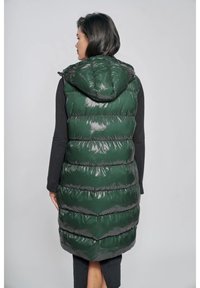 Zielona, błyszcząca kamizelka puchowa z kapturem, z poziomymi pikowanymi sekcjami, sięgająca do połowy łydki. Lekki materiał o gładkiej fakturze.