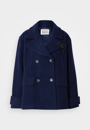 Marineblauer, doppelt geöffneter Wollmantel mit zwei vorderen Taschen, großen Revers und einem dekorativen schwarzen Schleifenakzent auf der Brust.