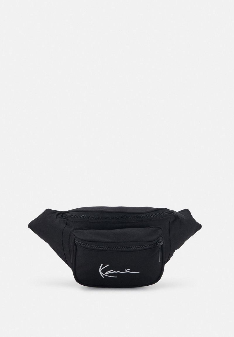 Mustaväriinen vyölaukku, jossa on kaksi vetoketjullista taskua, hopeinen brodeerattu logo, pehmeä tekstuuri ja tyylikäs, kompakti muotoilu.