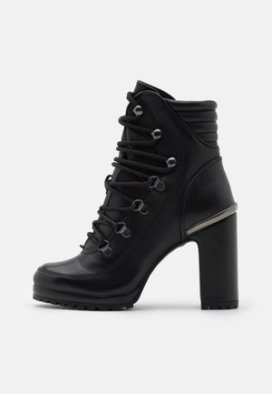 Bottine noire en cuir à talon haut, talon épais et carré, devant à lacets avec œillets métalliques, et col rembourré pour plus de confort.