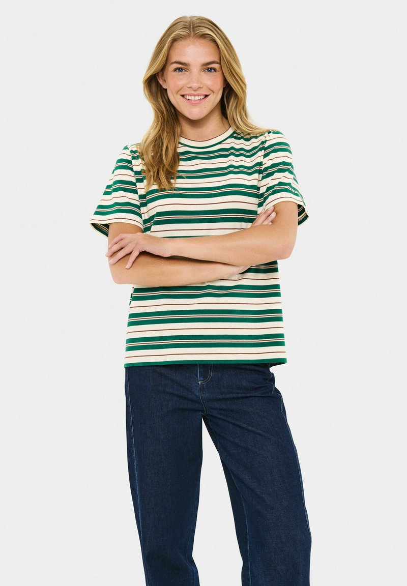 T-shirt rayé en vert, beige et crème, à manches courtes, encolure ronde, coupe décontractée, associé à un jean bleu foncé.