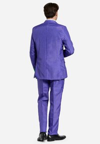 Completo a righe viola realizzato in un tessuto dalla texture liscia; presenta una vestibilità slim con pantaloni coordinati e completato da scarpe nere.