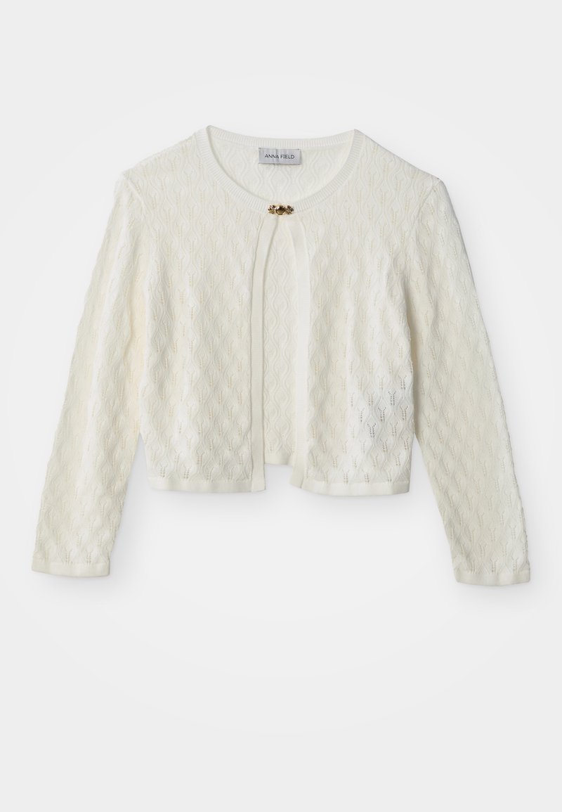Λευκό πλεκτό κοντό ζακετάκι με μακριά μανίκια, στρογγυλή λαιμόκοψη και μικρό διακοσμητικό χρυσό κούμπωμα στο κέντρο πάνω.