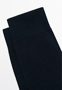 Granatowe bawełniane skarpetki z prążkowanym mankietem i gładką fakturą, starannie złożone, aby pokazać zbliżenie materiału i wzoru.