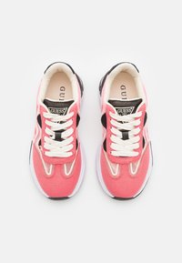 Baskets en toile rose avec accents noirs, lacets blancs, et semelle rembourrée, dotées d'un patch logo sur la languette et de superpositions texturées.