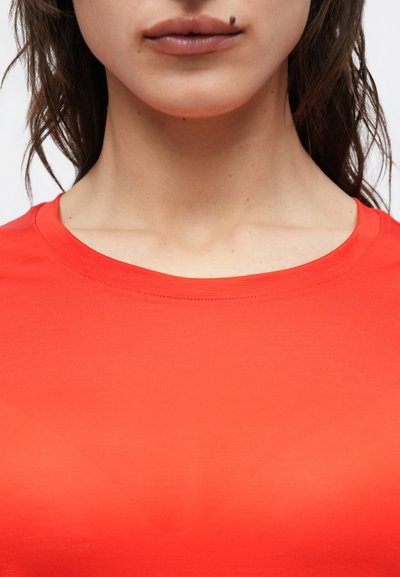 Piros pamut póló kerek nyakkivágással. Simogató tapintású és testhezálló szabású, finom átmenetes árnyékolással, a világos vöröstől a mélyvörösig.