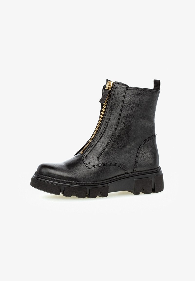 Botas de cuero negras hasta el tobillo con un zipper lateral, que cuentan con una suela gruesa, acentos cosidos y una lengüeta en el talón para facilitar su uso.