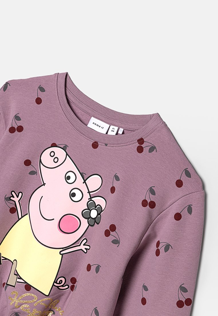 Lilak sweatshirt met kersenpatronen, featuring een cartoonvarkentje. Het ontwerp heeft een bloemenaccent en een geribde halslijn.