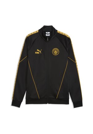 Zwarte jas met volledige rits, gouden bies, Puma-logo en tekst "KING" op de linkerborst, Manchester City-wapen op de rechterborst, en goudkleurige patroonstrepen op de mouwen.