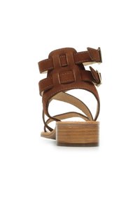 Sandalo in suede marrone con tacco a blocco, caratterizzato da ampie cinghie e due fibbie regolabili. Fodera interna liscia e suola texturizzata.