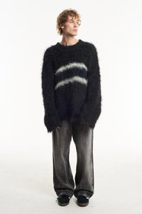Black fluffy sweater with white and dark stripes, paired with wide gray denim pants and black sneakers. Features long sleeves and relaxed fit.