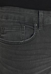 Tumedad hallid denim püksid kitsas lõikes, millel on tagatasku, kontrastne õmblus ja õrn tekstuur. Metallne nööp sulgemiseks vööl.