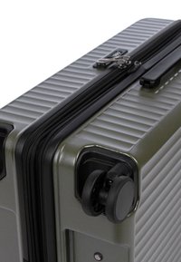 Valigia rigida di colore verde oliva con design a righe, dotata di una cerniera nera, maniglia e doppie ruote girevoli per una facile mobilità.