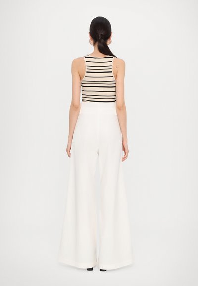 Top in cotone a righe beige abbinato a pantaloni bianchi a vita alta e gamba larga. Tessuto morbido con vestibilità rilassata. Design minimalista ed elegante silhouette.