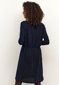 Námořnické modré šaty s dlouhými rukávy, lehkým materiálem s jemným leskem a elastickým pasem pro mírně přiléhavý střih.