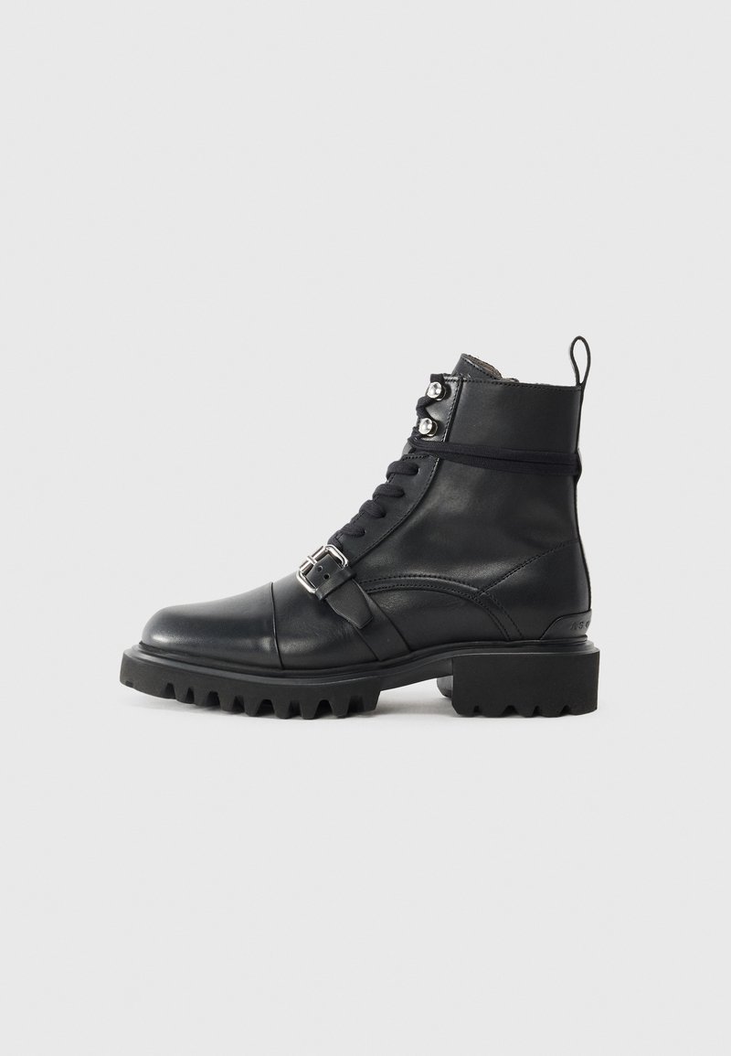 Stivaletto in pelle nera con punta rotonda, lace-up frontale, dettaglio con fibbia e suola spessa e robusta. Presenta accenti in metallo di tonalità argentata.