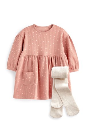 Robe bébé rose à manches longues avec des pois blancs, poche avant et deux boutons-pression sur l'épaule, associée à des collants crème pliés.