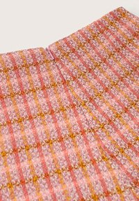 Gonna tessuta in motivo a quadri rosa e arancio con finitura testurizzata; presenta una discreta chiusura con zip sul retro.