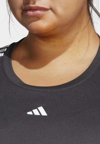 Svart treningstrøye med rund hals, utstyrt med en hvit logo og tekstur. Stoffet ser glatt ut med en tettsittende design.