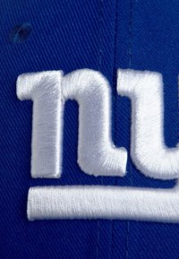 Gorra azul con texto bordado en blanco "NY" en la parte frontal. La tela tiene un acabado texturizado, y las costuras son prominentes con contornos claros.