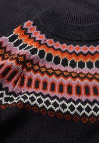 Pletený svetr se štíhlým základním tmavým materiálem a geometrickými, vícebarevnými vzory v oranžové, růžové, černé a bílé barvě. Hladký výstřih a manžety.