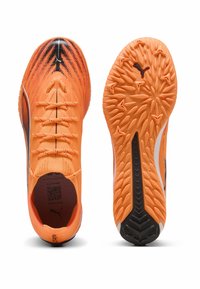Orange Fußballschuhe mit einem atmungsaktiven Obermaterial aus Mesh, schwarzen Akzenten und einer strukturierten Außensohle mit einem Muster aus erhabenen Rillen.