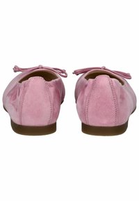 Ballerines en daim rose avec un bout arrondi, des nœuds attachés sur chaque chaussure et une semelle en caoutchouc marron. Texture douce avec des détails cousus.