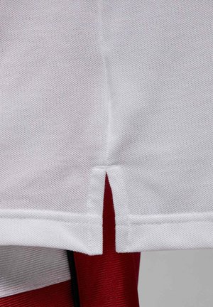 Valkoinen teksturoitu kangas, jossa pieni pystysuora viilto ylhäällä ja alla punainen teksturoitu materiaali, jotka yhdessä muodostavat kerroksellisen tekstiilisuunnittelun.