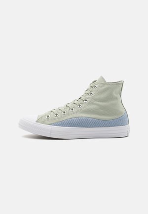 Baskets montantes en toile vert clair avec un accent en tissu bleu texturé et une semelle en caoutchouc blanc. Comprend des œillets en métal et des lacets plats.