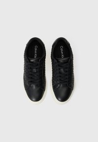 Sneaker in pelle nera con pannello laterale testurizzato, punta rotonda e suola in gomma bianca. Include i lacci e il logo del marchio sulla linguetta.