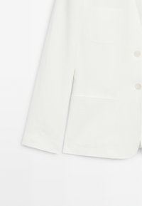 Blazer bianco a maniche lunghe con due tasche anteriori a pattina e due bottoni sulla parte anteriore, mostrato su uno sfondo bianco.