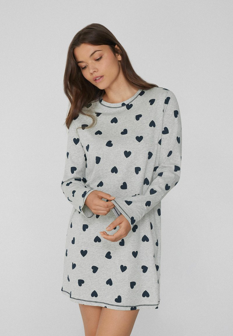 Camicia da notte grigia a maniche lunghe realizzata in tessuto morbido, con un motivo di cuori blu navy, scollatura rotonda e maniche leggermente svasate.