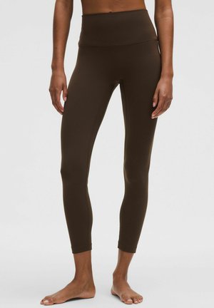 Brązowe legginsy z wysokim stanem wykonane z gładkiej, elastycznej tkaniny, o dopasowanym kroju i długości do kostek. Brak widocznych wzorów czy elementów metalowych.