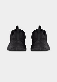 Paire de chaussures de sport noires vues de dos avec des languettes de tirage et des semelles texturées sur un fond gris uni.