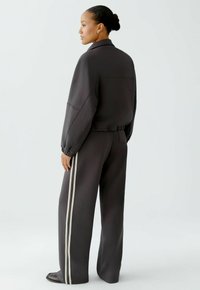 Dunkelgraues, übergroßes Sweatshirt mit weiten Ärmeln, kombiniert mit passenden weiten Hosen mit weißen seitlichen Streifen und elastischem Bund.