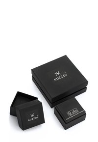 Tre svarta, matta smyckeskrin, två stängda och ett öppet, alla med "Kuzzoi"-logotypen och ett märkt som återvunnet papper, på vit bakgrund.