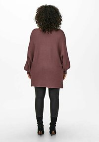 Oversized mörkröd tröja med ribbad textur, långa ärmar och lös passform, kombinerad med svarta läderleggings och knähöga svarta stövlar.