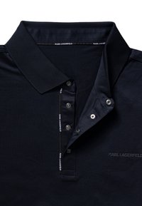 Granatowa koszulka polo z gładkiej tkaniny, z klasycznym kołnierzykiem, plisą na trzy guziki i dekoracyjnymi akcentami z logo.