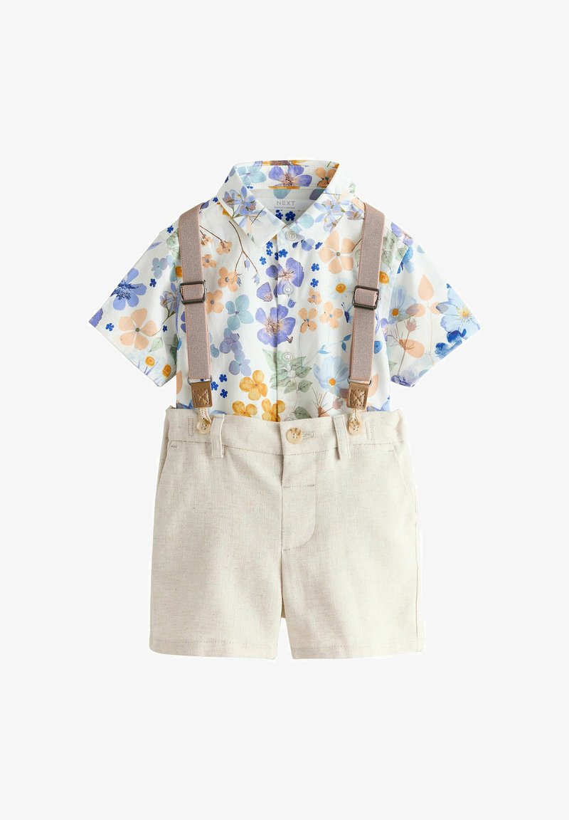 Camicia a maniche corte con fiori azzurri, arancioni e viola; pantaloncini beige con bretelle e chiusure con bottoni. Tessuto di cotone morbido.