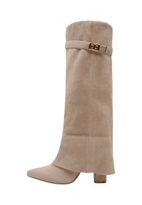 Botte à talon en daim beige avec un bout pointu, une tige haute et une fermeture à boucle dorée décorative autour de la cheville. Texture lisse, design minimaliste.