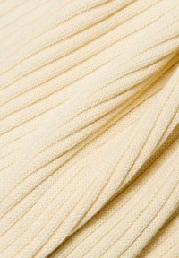 Helle gelbe Strickware mit einer gerippten Textur und abwechselnden Reihen, die ein dezentes Muster bildet. Glatte Oberfläche, weiches Aussehen.